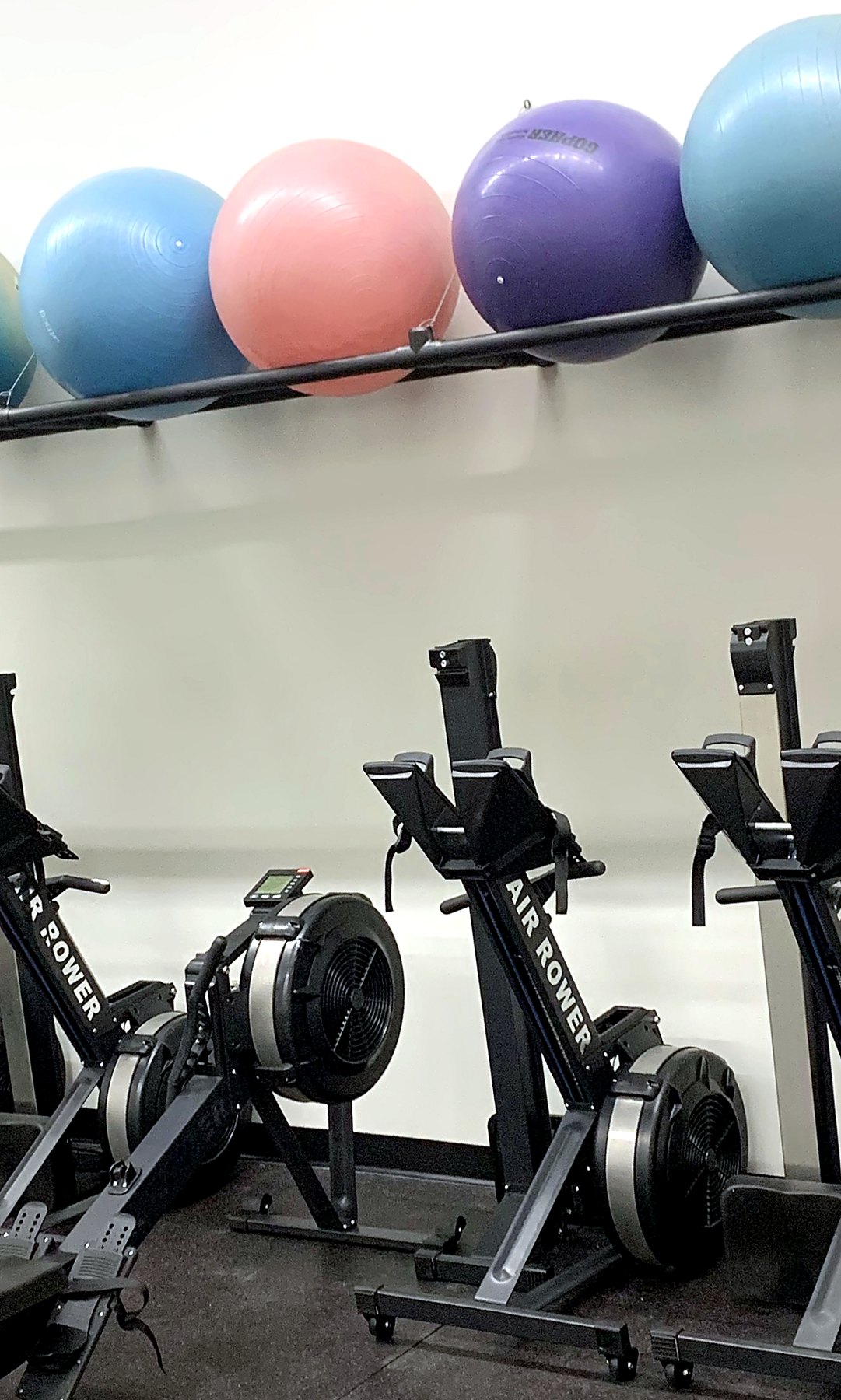 A row of air rowers below a rack of exercise balls