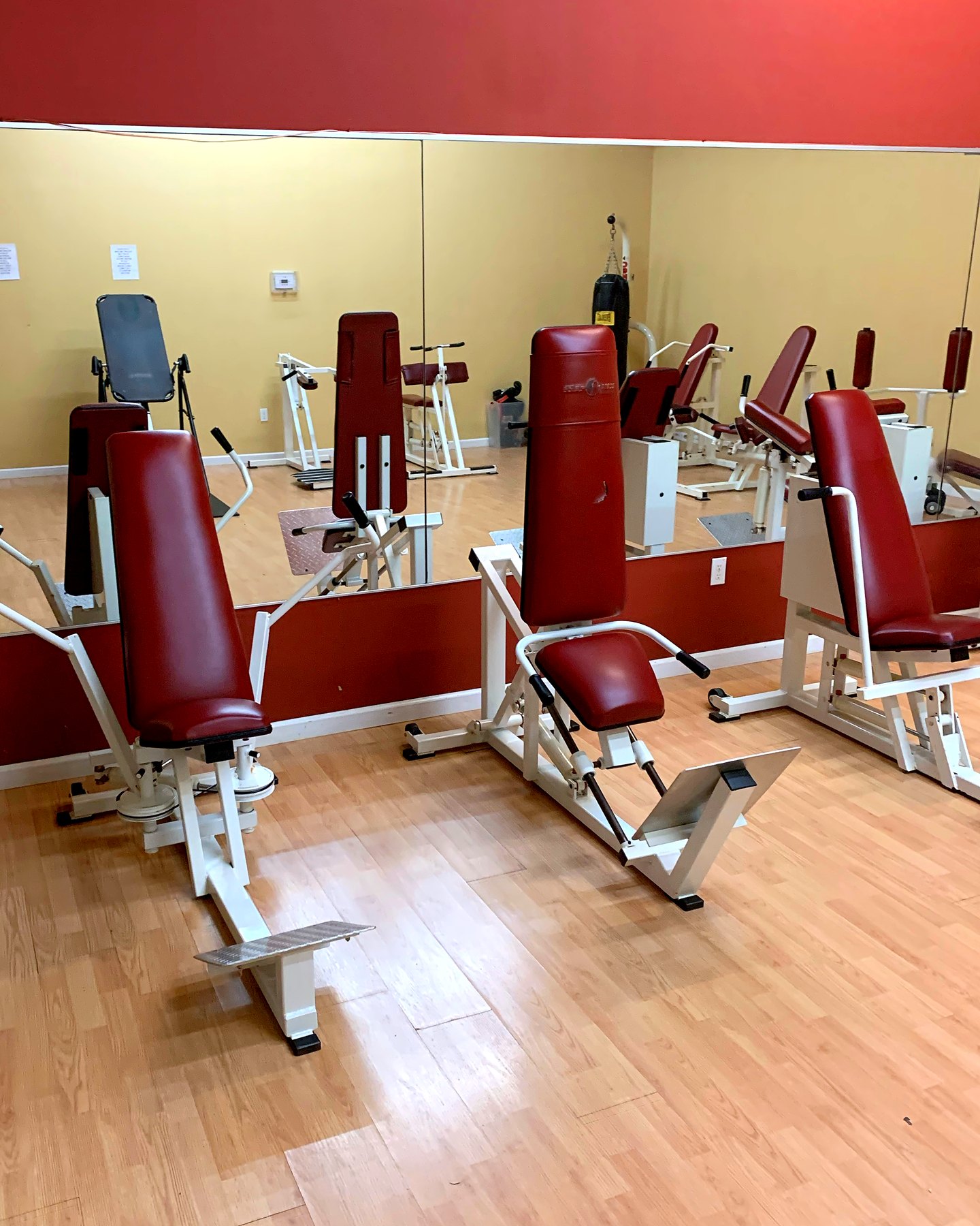 Circuit machines with maroon seats on a wood floor in front of a mirrored wall